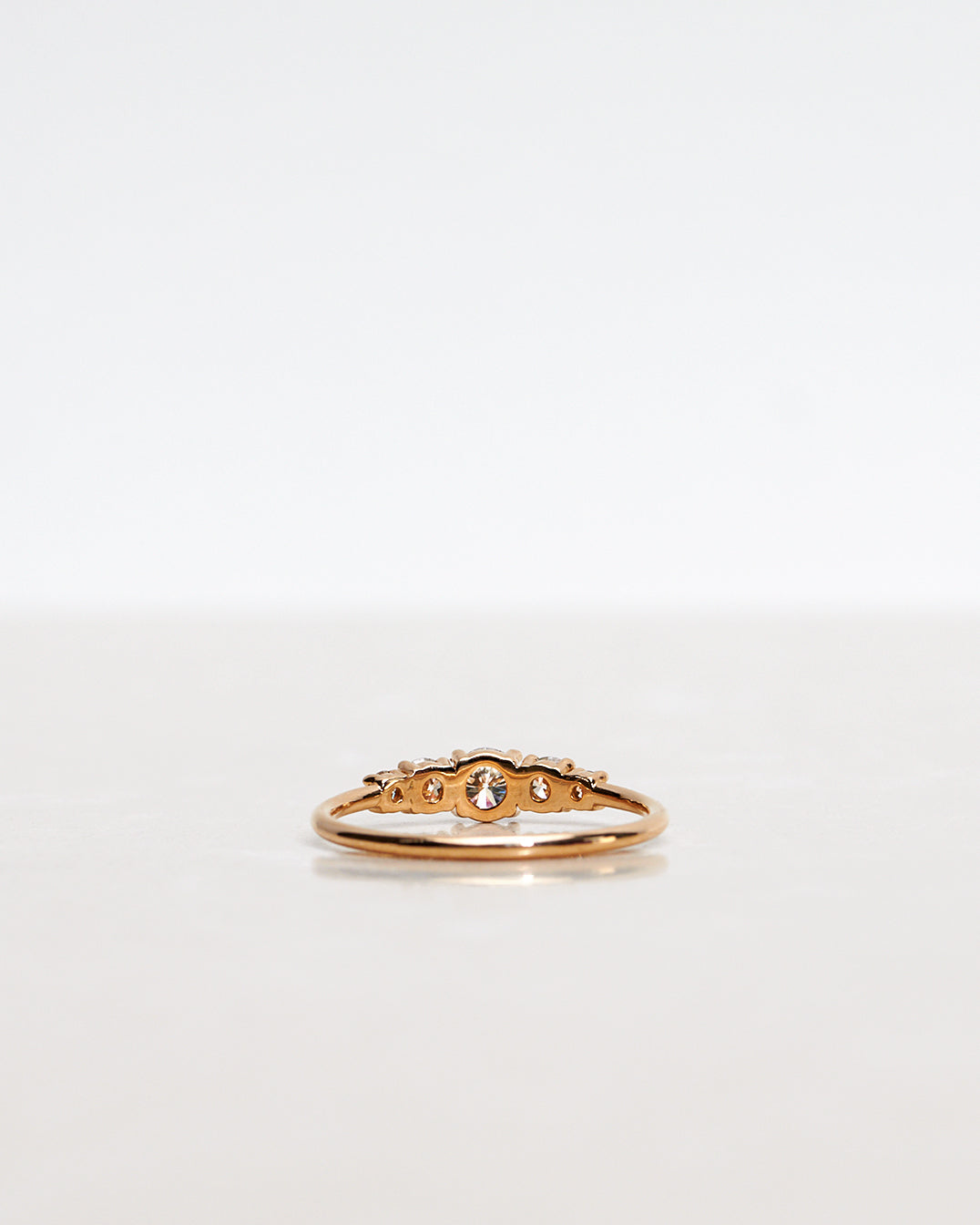 Mumbaistockholm Fine Jewelry Ring: Elise Ring in 18K yellow gold with five white, conflict-free diamonds. The center diamond is 0.25 CT, and on each side are two 0.11 CT diamonds, and two 0.04 CT diamonds. Pictured from the back.