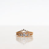 Ring stack with three Mumbaistockholm Fine Jewelry Rings: Elise Ring in 18K yellow gold with five white, conflict-free diamonds, Jade Petite Wave Half Ring with a curved band half covered with 0.005 CT diamonds TWVS, and Five Diamond Triangle Ring with five 0.02 CT diamonds TWVS.